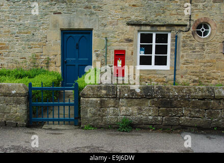 Fassade eines Hauses im Dorf Edensor, Derbyshire: gibt es ein roten Royal Mail-Briefkasten in die Wand gesetzt. Stockfoto