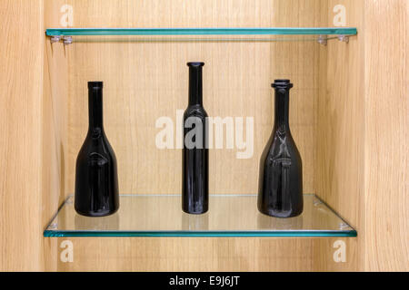 Drei schwarze Leergut auf ein Glas Regale in ein Holzgehäuse Stockfoto