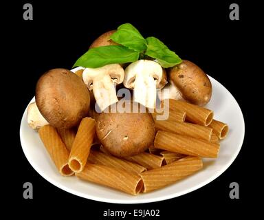 Baby Bella Pilze, Pasta und Basilikum auf einem schwarzen Hintergrund. Stockfoto