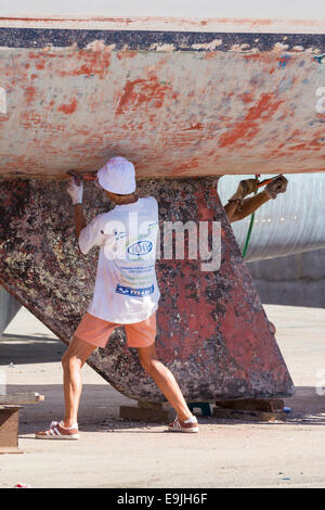 Schaben Lack Yacht Rumpf in Marina Reparaturwerft in Kanarische Inseln Stockfoto