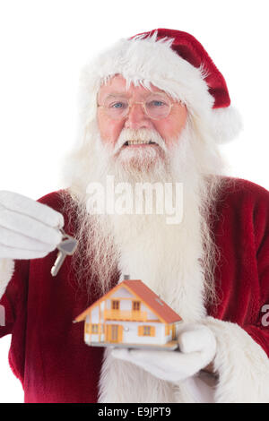 Santa übergibt den Schlüssel an ein kleines Haus Stockfoto