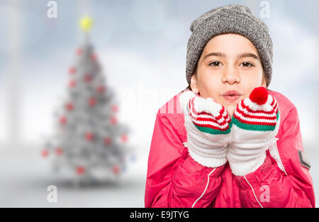 Zusammengesetztes Bild eingepackt kleines Mädchen bläst über Hände Stockfoto