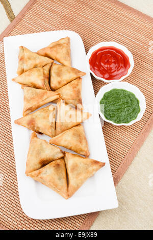 Draufsicht der köstlichen tief gebraten südindische Samosas mit Minze-Chutney und Tomatensauce. Stockfoto