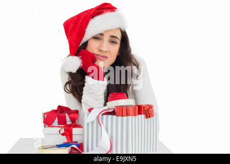 Unsicher, Brünette in Nikolausmütze Verpacken Geschenke Stockfoto