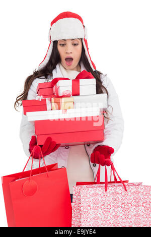 Überrascht Brünette in Winterkleidung hält viele Geschenke und Einkaufstaschen Stockfoto