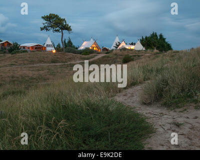 Luxus-Camping in Küstendünen unter Pinien Holz über ein Feld Gras und Zaun nach Sonnenuntergang betrachtet Stockfoto