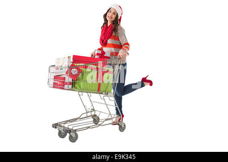 Festliche Brünette schieben Wagen voller Geschenke Stockfoto