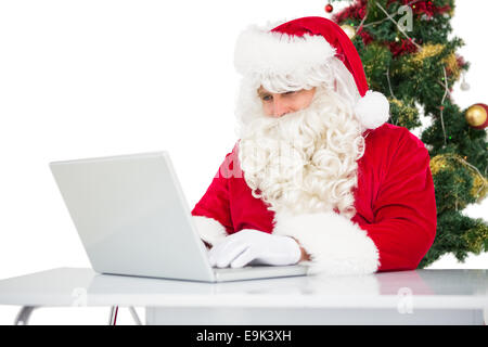 Weihnachtsmann mit seinem Laptop in der Nähe von Weihnachtsbaum Stockfoto