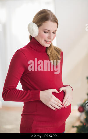Schwangere Frau macht ein Herz mit den Händen auf den Bauch Stockfoto