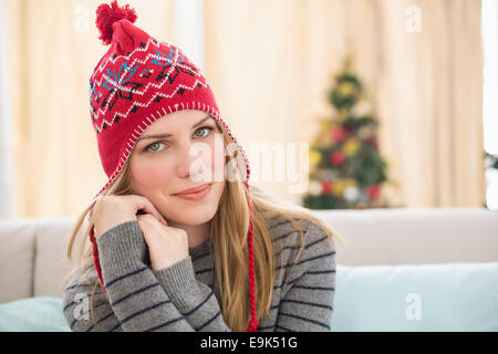 Hübsche Blondine in Winterkleidung sitzen auf der couch Stockfoto