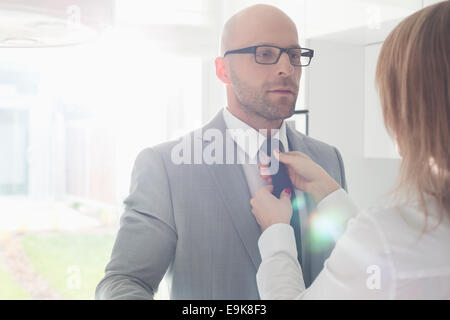 Frau, die Anpassung der Geschäftsmann Krawatte zu Hause Stockfoto