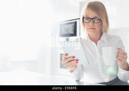 Schöne Mitte adult Geschäftsfrau Kaffeetrinken mit Tisch-PC zu Hause Stockfoto