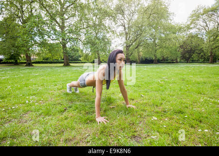 Voller Länge jungen Fit Frau Durchführung Liegestütze im park Stockfoto