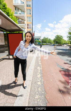 In voller Länge Portrait von lächelnden Geschäftsfrau hagelt Taxi auf Straße Stockfoto