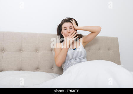 Verschlafene Frau Gähnen im Bett Stockfoto
