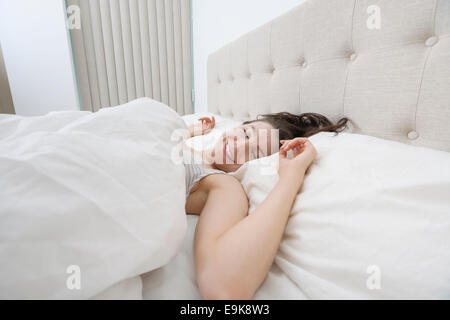 Lächelnde Frau schläft im Bett Stockfoto