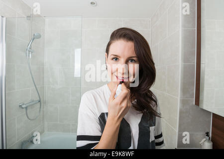 Porträt der jungen Frau Auftragen von Lippenstift im Badezimmer Stockfoto