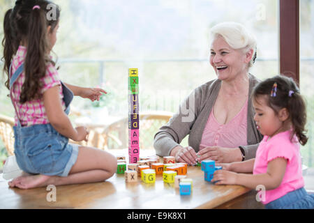 Glückliche Großmutter und Enkelinnen mit Alphabet Blöcke am Tisch spielen Stockfoto