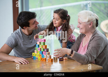 Mädchen spielen mit Alphabet Blöcke von Vater und Großmutter am Tisch im Haus Stockfoto