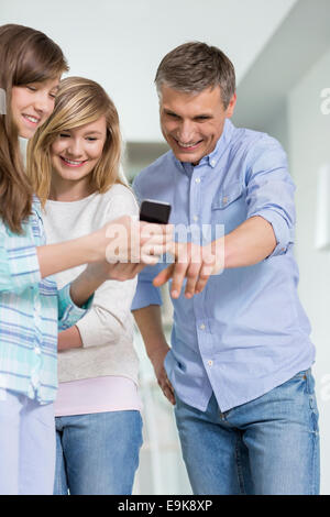 Vater und Töchter mit Smartphone zu Hause Stockfoto