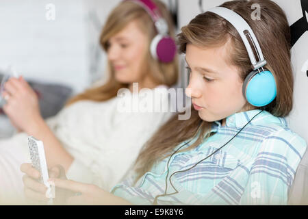 Schwestern hören Musik über Kopfhörer zu Hause Stockfoto