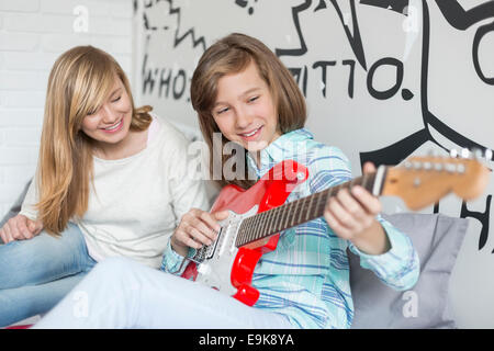 Mädchen, die Schwester, die Gitarre zu Hause anhören Stockfoto