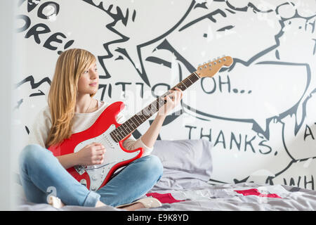 Der Teenager Mädchen spielt Gitarre im Schlafzimmer in voller Länge Stockfoto