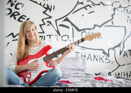 Porträt der Teenager Mädchen spielt Gitarre im Schlafzimmer Stockfoto
