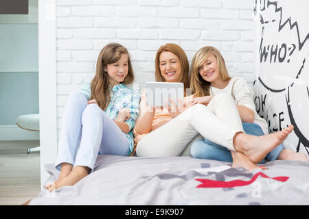 Mutter mit Töchtern mit Tablet PC im Schlafzimmer Stockfoto