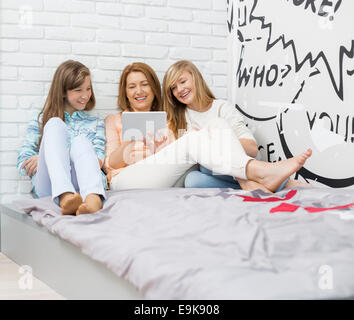 Mutter mit Töchtern mit digital-Tablette im Schlafzimmer Stockfoto