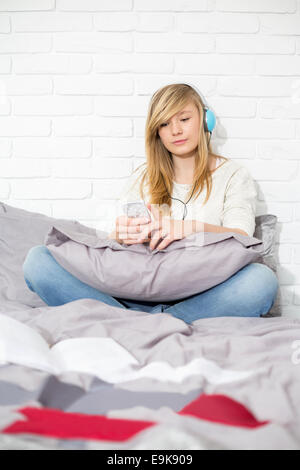 Teenager-Mädchen Musikhören im Schlafzimmer in voller Länge Stockfoto