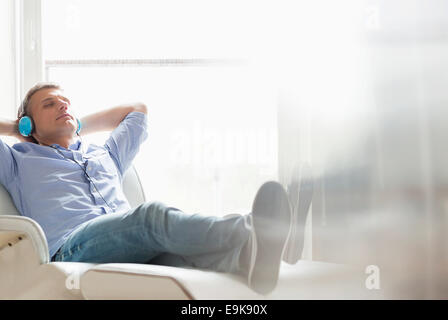 Der entspannte Mann mittleren Alters Musikhören zu Hause in voller Länge Stockfoto