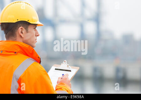 Rückansicht des Mitte erwachsenen Mannes in Zwischenablage im Frachthafen schreiben Stockfoto