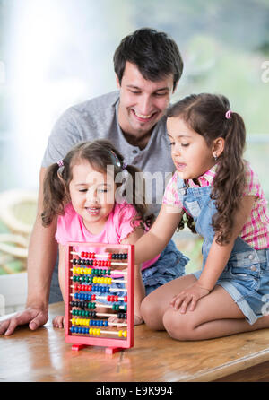 Glücklicher Vater und Töchter spielen mit Abacus im Haus Stockfoto