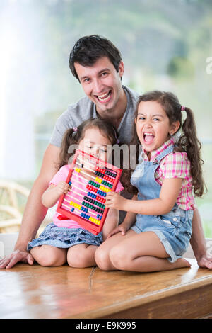 Porträt der glückliche Vater und Töchter spielen mit Abacus im Haus Stockfoto