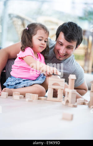 Kleine Mädchen und Vater spielen mit Holzbauklötzen Erdgeschoss Stockfoto