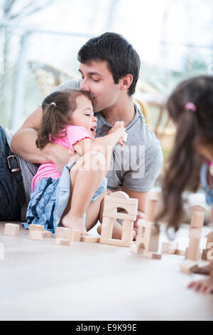 Liebender Vater Tochter Building Blocks im Boden küssen Stockfoto