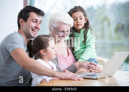Glücklich drei-Generationen-Familie mit Laptop am Tisch im Haus Stockfoto