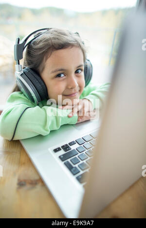 Porträt von netten Mädchen Musik über Kopfhörer hören, während mit Laptop zu Hause Stockfoto