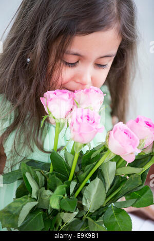 Niedliche Mädchen riechen Rosen zu Hause Stockfoto