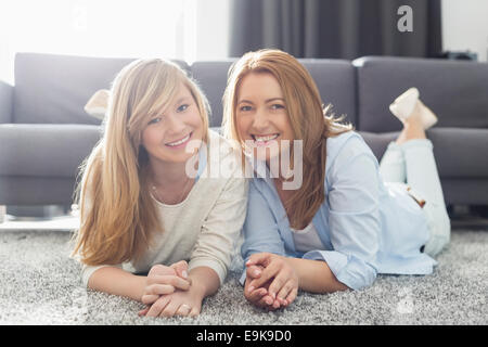 Porträt des Lächelns, Mutter und Tochter auf Teppich liegend Stockfoto