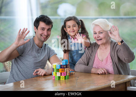 Portrait von senior Frau mit Sohn und Enkelin winken Hände am Tisch Stockfoto