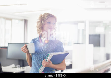 Geschäftsfrau, Kaffeetrinken im Kreativbüro mit gedrückter Dateien Stockfoto