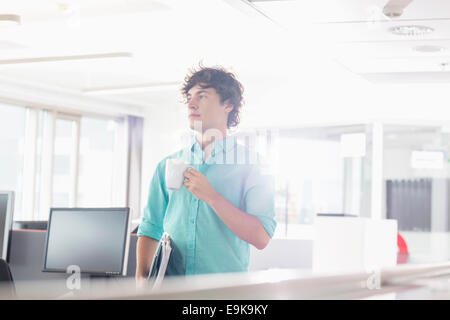 Geschäftsmann, Kaffeetrinken im Kreativbüro mit gedrückter Dateien Stockfoto