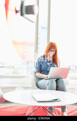 Junge Geschäftsfrau mit Laptop in Kreativbüro Stockfoto