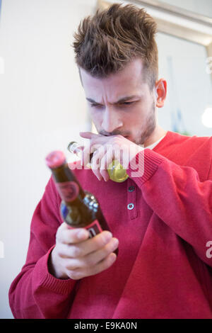 Junger Mann lesen Etikett Bierflasche im café Stockfoto