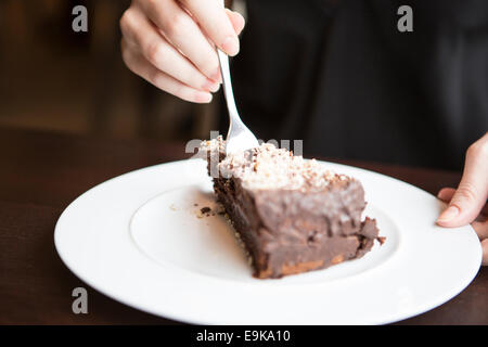 Nahaufnahme von Frauenhand schneiden Schokolade Gebäck Stockfoto