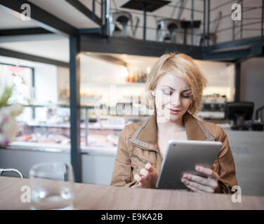Schöne junge Frau, die mit digital-Tablette im café Stockfoto