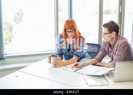 Kreative Geschäftskollegen lesen Datei zusammen am Schreibtisch im Büro Stockfoto