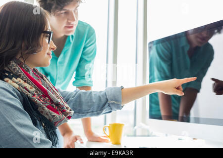 Kreative Geschäftsfrau zeigt etwas an Kollegen auf Desktop-Computer im Büro Stockfoto